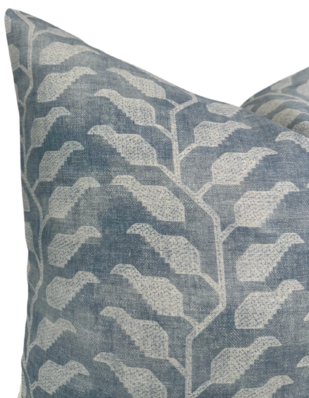 Close-up of a pillow cover in muted lake blue with an off-white geometric leaf pattern, showing textured woven fabric detail and sharp corner stitching.