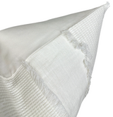 Ivory pillow cover featuring multiple woven textures including ribbed, waffle, and fringed sections, displayed with its corner lifted to reveal fabric detail.