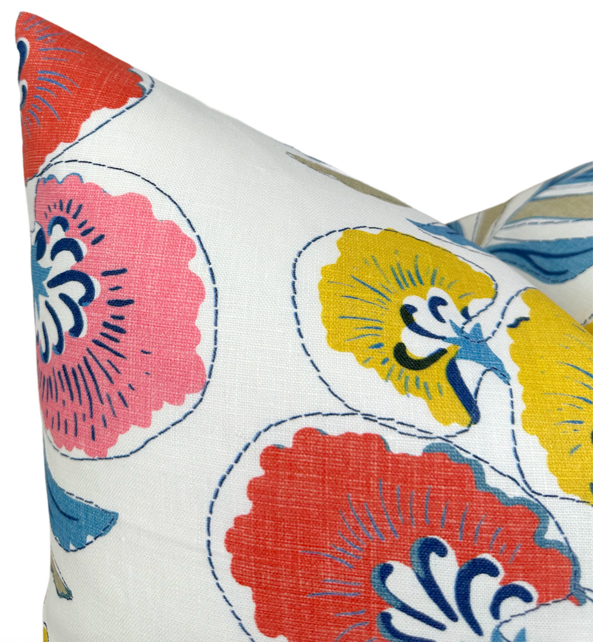 Close-up of a pillow with coral and yellow stylized floral patterns outlined in navy blue on white fabric, highlighting vibrant, large flower shapes and delicate leaf details.