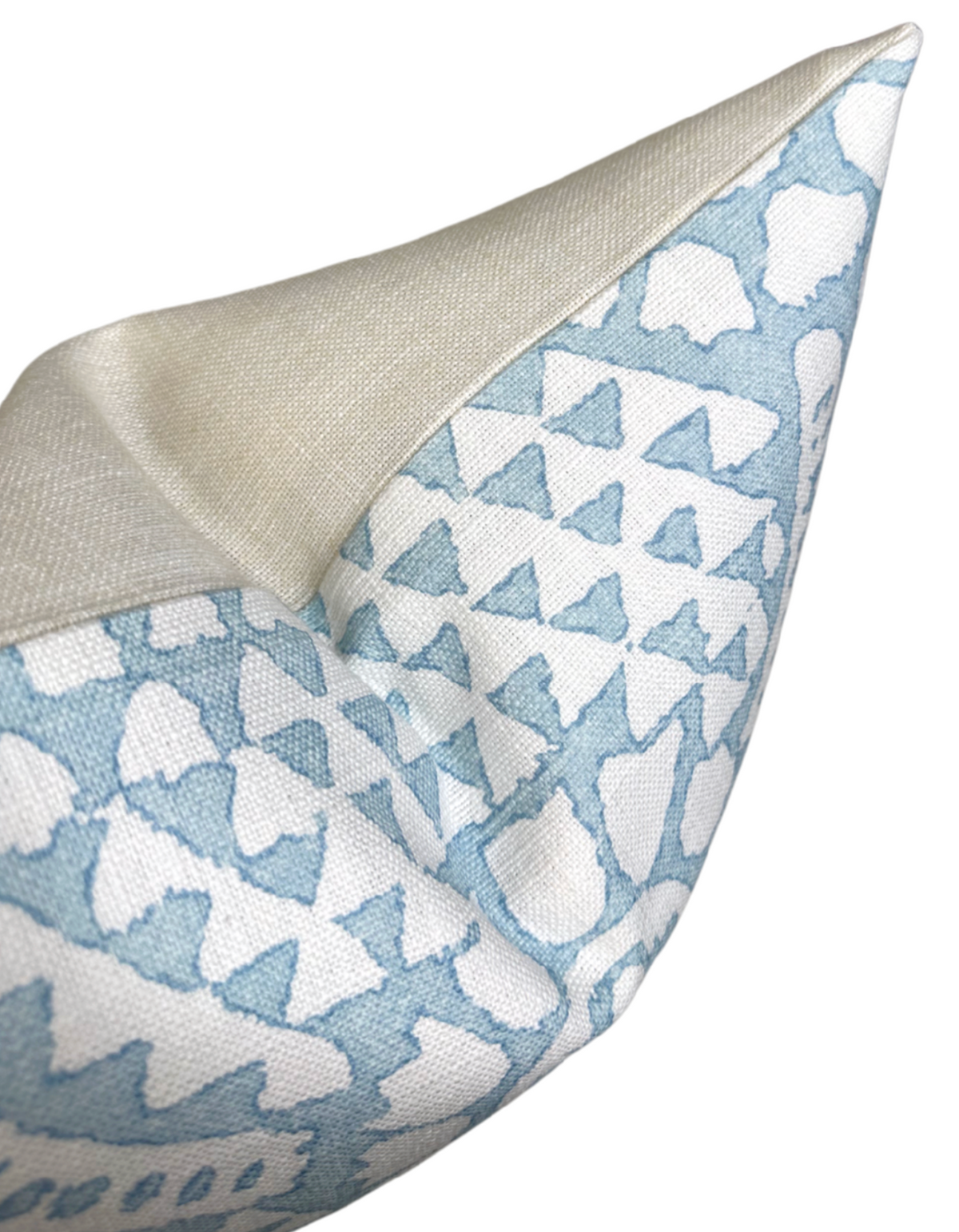 Close-up of a pillow corner with a chamomile-inspired print in spa blue and white on textured fabric, featuring a plain beige reverse side.