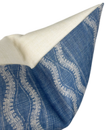 Corner of a Zanzibar Pillow Cover in indigo blue with white textured woven wavy pattern and a smooth off-white fabric on the reverse side, shown close up.