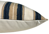 Close-up side view of a pillow with a striped cover featuring vertical beige, black, and white stripes and a white zipper along the bottom edge on a plain white background.