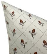 Cream-colored pillow cover patterned with diagonal dotted lines forming diamonds, each containing a small stylized brown and green botanical motif.