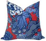 Square pillow with bold red background featuring large blue and white floral and leaf patterns in varying shades of blue.