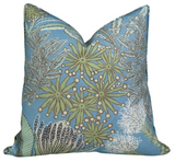 Square pillow cover with spa blue background featuring botanical prints of green protea flowers and detailed fern leaves in white and black outlines.