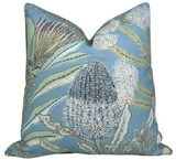 Square pillow cover with a spa blue background featuring detailed protea flowers and delicate fern leaves in shades of green, white, and brown.