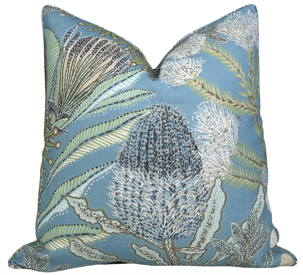 Square pillow cover with a spa blue background featuring detailed protea flowers and delicate fern leaves in shades of green, white, and brown.