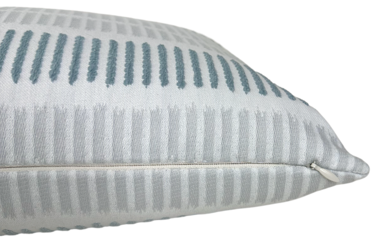 Close-up of a cushion with vertical rectangular patterns in slate blue and sterling gray on a white background, showing the textured fabric and sewn edge.