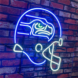 Neon sign of a Seattle Seahawks football helmet in bright blue, white, and green lights mounted on a red brick wall.