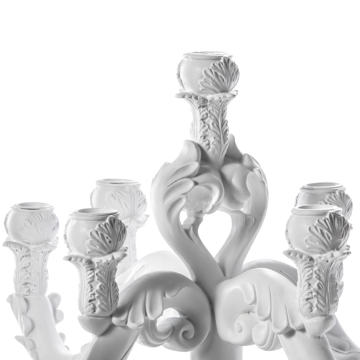 White sculpted chandelier-like object with six ornate candle holders featuring leaf and scroll motifs, arranged symmetrically around a central stem, set against white background.