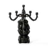 Black sculpted candelabra featuring three monkeys covering their eyes, ears, and mouth, holding five curved candle holders above them.