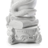 White sculptural base featuring coiled snake over books labeled 'Aristoteles' and 'Hamlet' above ornate pedestal inscribed 'BURLESQUE' with decorative detailing.