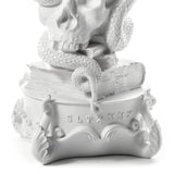 White sculpture featuring a skull resting on stacked books with a snake coiled around them, set on an ornate base stamped with 'SLT MMX'.