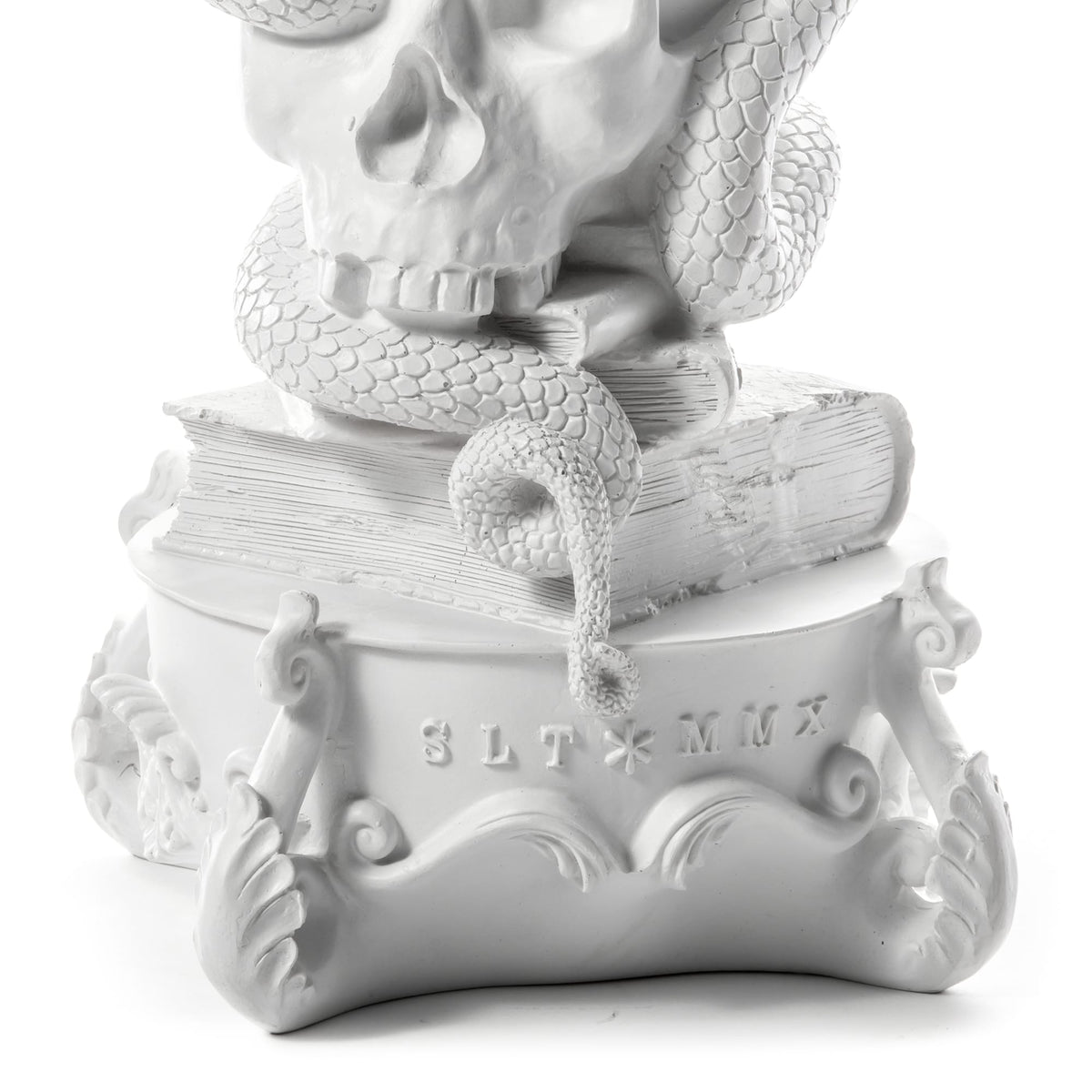 White sculpture featuring a skull resting on stacked books with a snake coiled around them, set on an ornate base stamped with 'SLT MMX'.