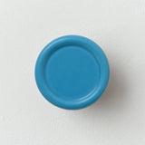 Round blue coat hook with a concave center mounted on a white wall, showing a smooth matte finish and simple modern design.