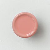 Round, smooth coat hook with a glossy, soft pink finish, viewed from above against a plain light gray wall.
