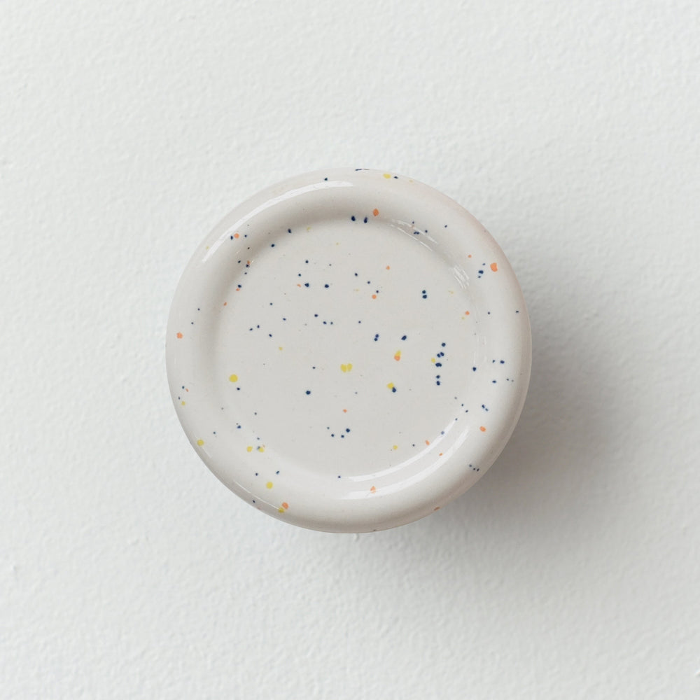 Sequence coat hook - Revolve in speckle color, showing curved ceramic form on white wall