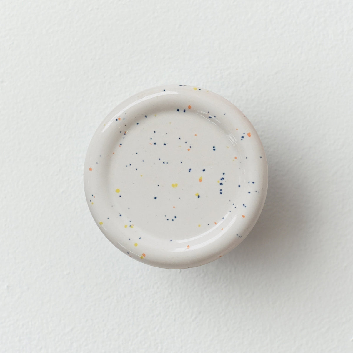 Sequence coat hook - Revolve in speckle color, showing curved ceramic form on white wall