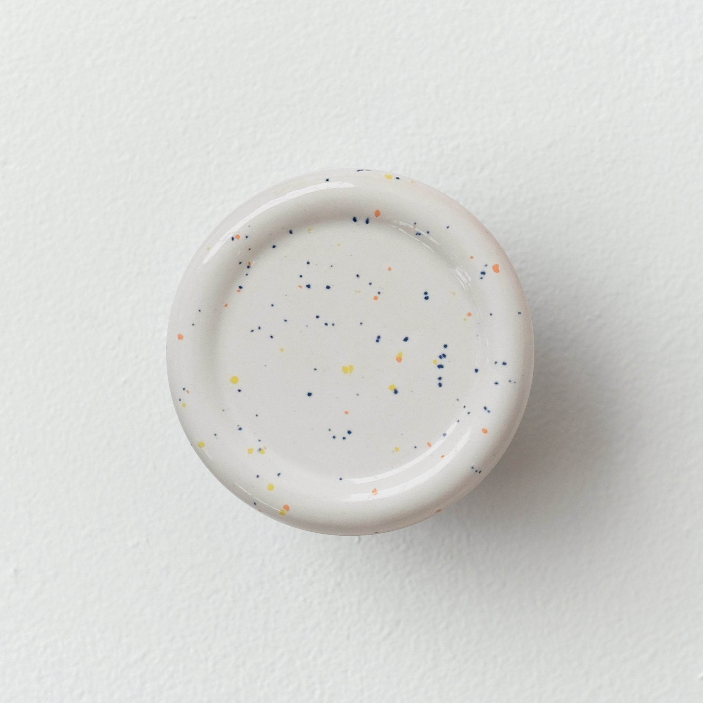 Sequence coat hook - Revolve in speckle color, showing curved ceramic form on white wall