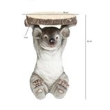 Small koala-shaped side table holding a round wood slab with bark edges, detailed in gray and brown tones, 52 cm tall with a 35 cm diameter top.