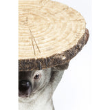 Close-up of a koala figurine holding a round wood slice table top with visible tree rings and textured bark edge.