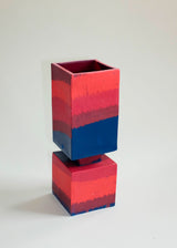 Short squared vase with stacked cube and rectangular prism, featuring horizontal bands of red, pink, and dark blue colors with textured gradient effect.