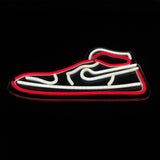 LED neon light shaped like a sneaker, outlined in red with white interior detailing on a black background.