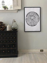 Black and white print of a Douglas Fir tree cross-section showing detailed growth rings, framed and hung on a gray wall above a black drawer cabinet.