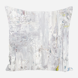 Square pillow with a soft abstract design featuring vertical brushstrokes in white, gray, and faint hints of yellow and blue on a light background.