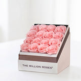 Square white box filled with 16 light pink roses, displayed elegantly