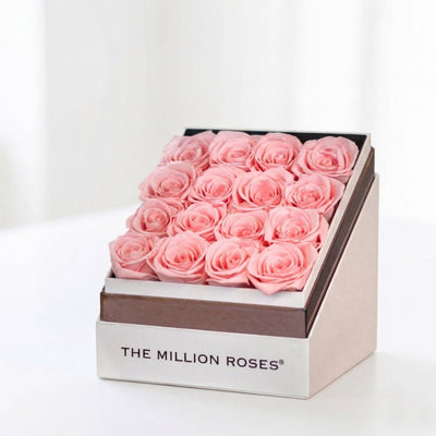 Square white box filled with 16 light pink roses, displayed elegantly