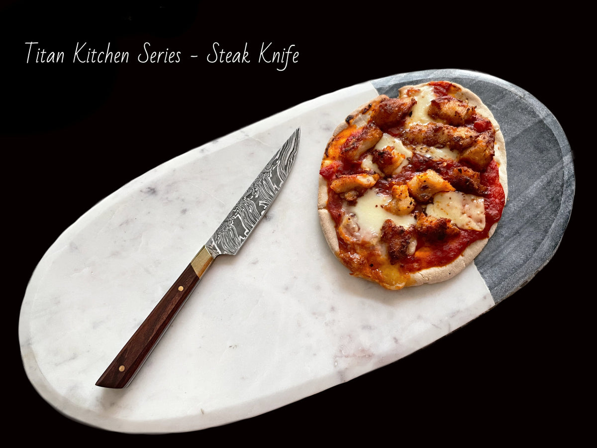 Damascus Steel Steak Knife with rosewood handle resting on a wooden cutting board