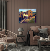 Colorful painting of a sunlit street lined with buildings, featuring a prominent church with an arched entrance under a blue sky, displayed above a modern brown sofa.