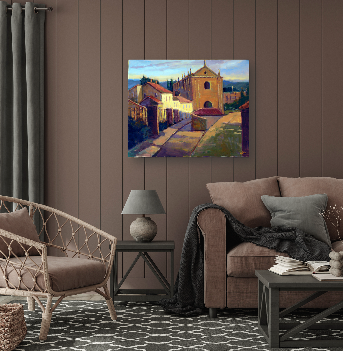 Colorful painting of a sunlit street lined with buildings, featuring a prominent church with an arched entrance under a blue sky, displayed above a modern brown sofa.