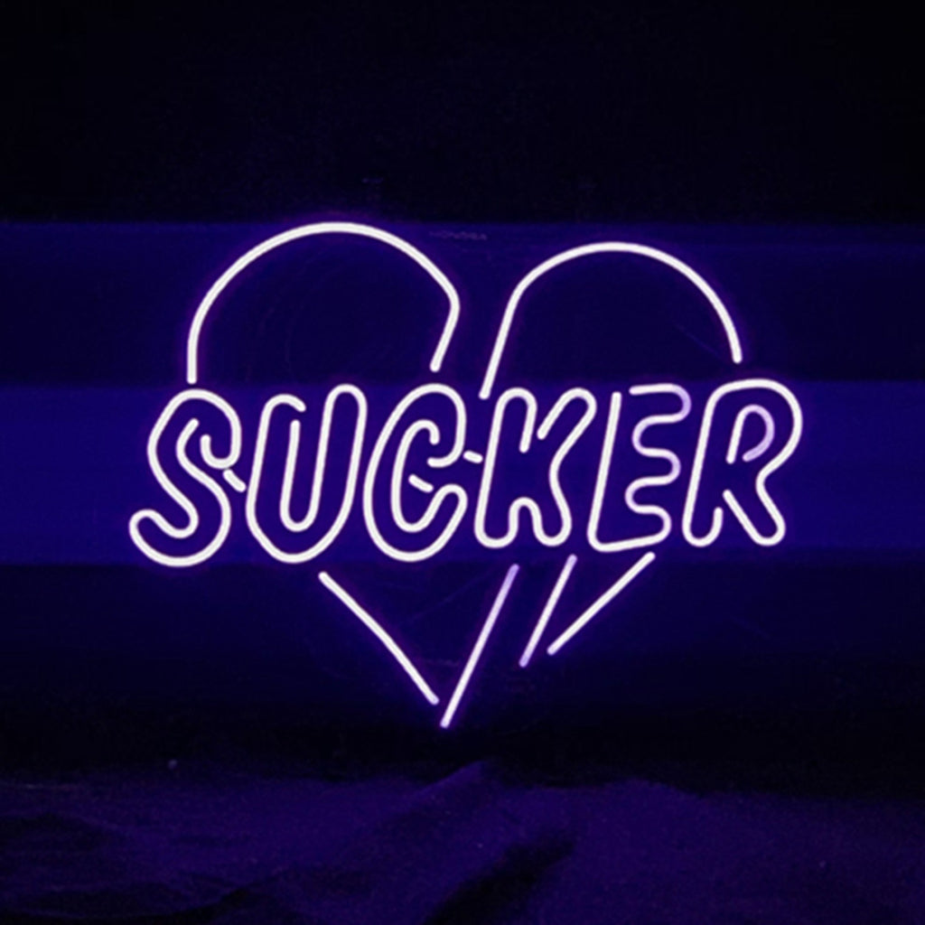 Purple neon sign displaying the word 'SUCKER' with the letters enclosed inside a stylized heart outline on a black background.
