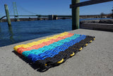 Sunset-inspired lobster rope mat with stripes of black, blue, teal, orange, and yellow
