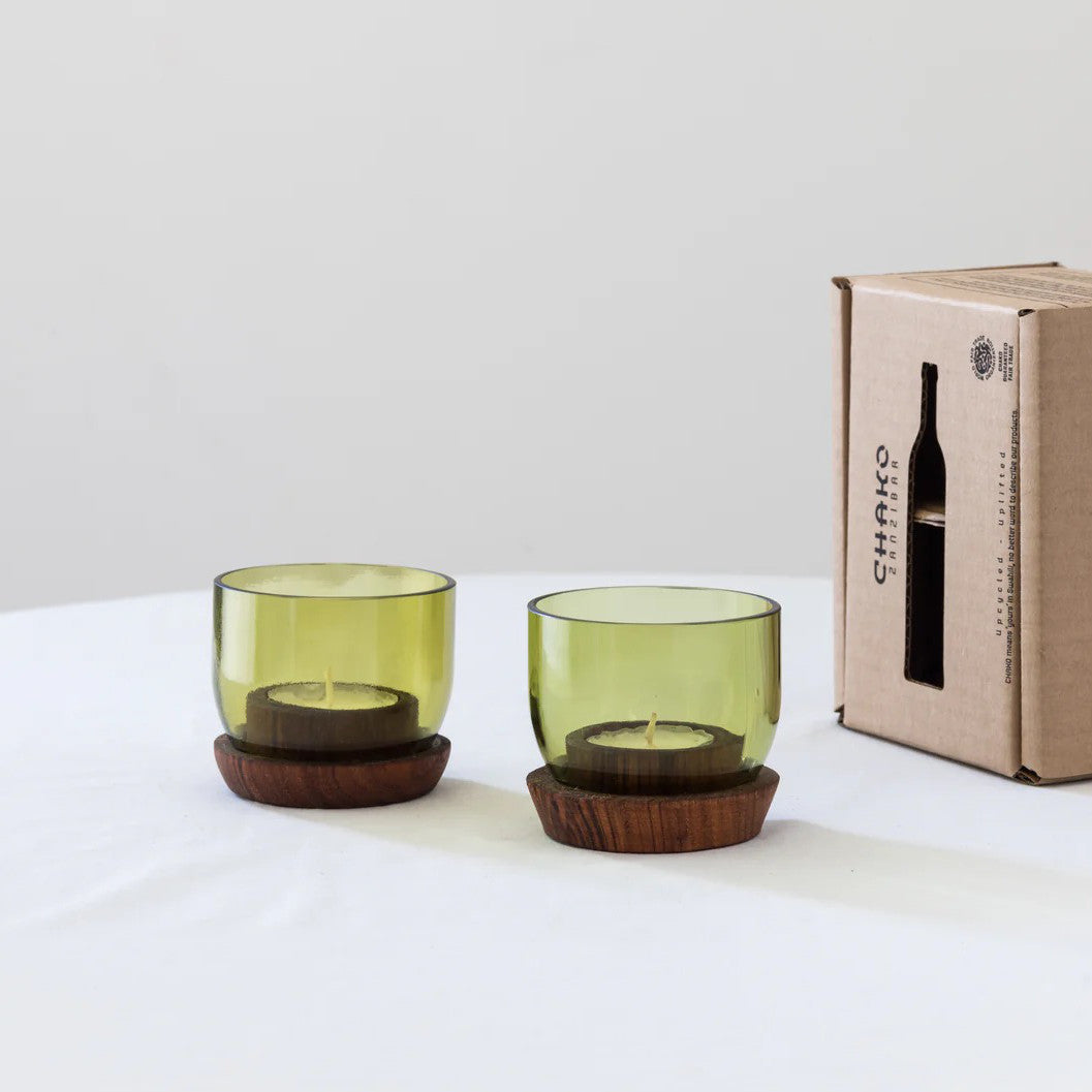 Two short Taa Candle Holders with olive green glass and dark wooden bases, side by side on a plain surface.