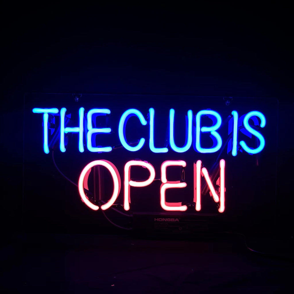 Neon sign with blue lettering 'THE CLUB IS' above pink lettering 'OPEN' on a dark background