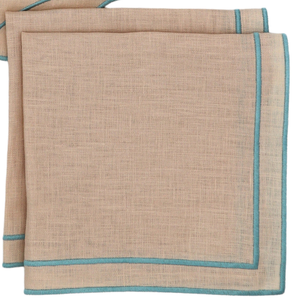 Two beige linen napkins with blue embroidered edges, folded on a wooden surface