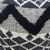 Close-up of a decorative pillow featuring a black and white tufted chevron pattern with diamond shapes forming a textured geometric design.