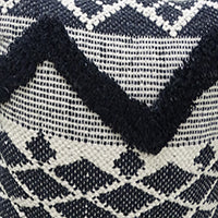 Close-up of a decorative pillow featuring a black and white tufted chevron pattern with diamond shapes forming a textured geometric design.