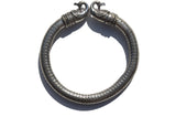Antique Norse Viking bracelet with two detailed peacock heads facing each other and a dotted pattern along the thick metal band, shown from above.