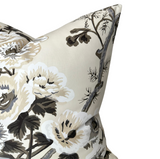 Close-up of a charcoal-colored pillow cover with a print of large white and beige hollyhock flowers and dark gray branches on a light background.