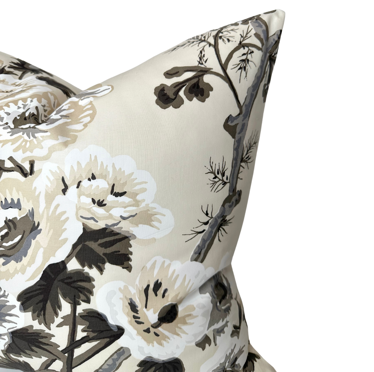 Close-up of a charcoal-colored pillow cover with a print of large white and beige hollyhock flowers and dark gray branches on a light background.