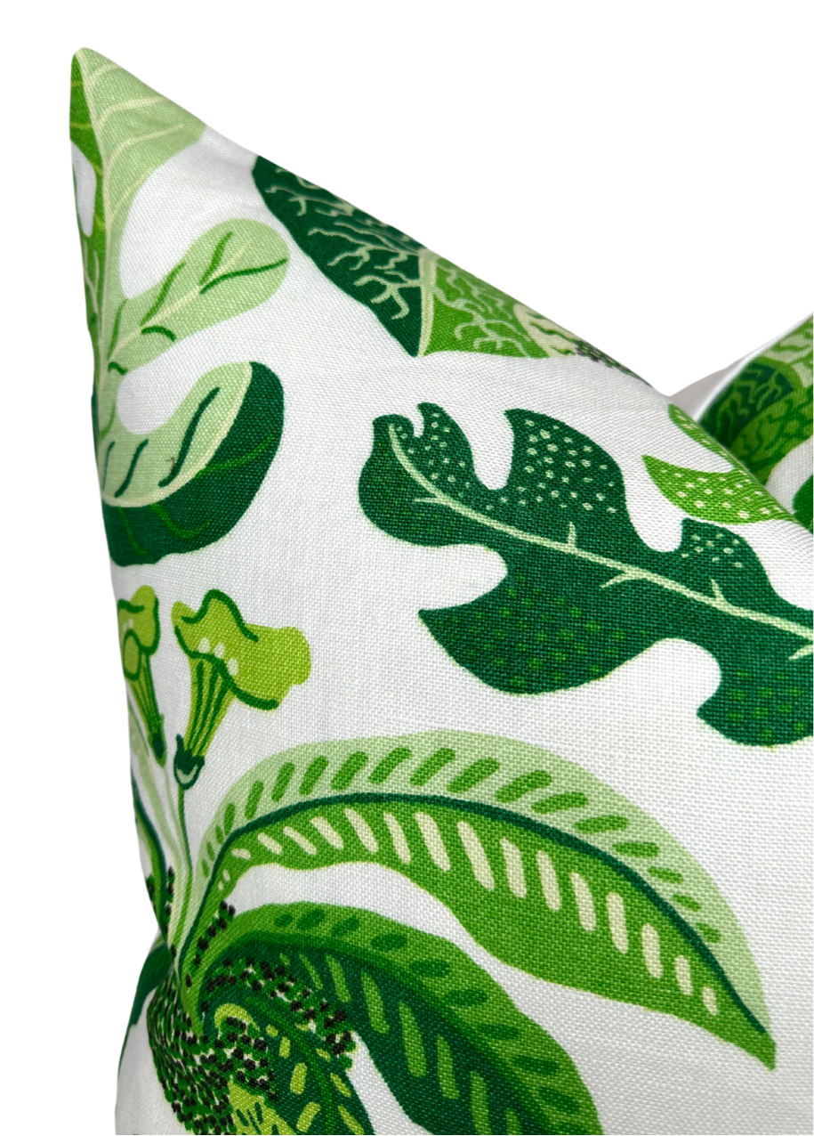 Corner of a leaf green pillow cover with various large tropical leaf patterns in shades of green on white fabric, highlighting detailed leaf veins and shapes.
