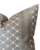 Close-up of a pillow cover in earth grey with white geometric and dotted patterns, featuring a textured woven fabric from McLaurin + Piercy Textiles.