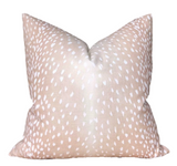Pink pillow cover with antelope print lying on a beige couch