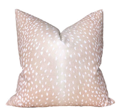 Pink pillow cover with antelope print lying on a beige couch
