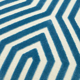Close-up of a velvet fabric with a marine blue geometric maze pattern on a light beige background, showing soft texture and raised design.