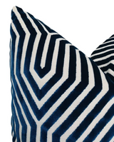 Close-up of a navy blue velvet pillow with a white geometric chevron pattern creating a striking angular design.